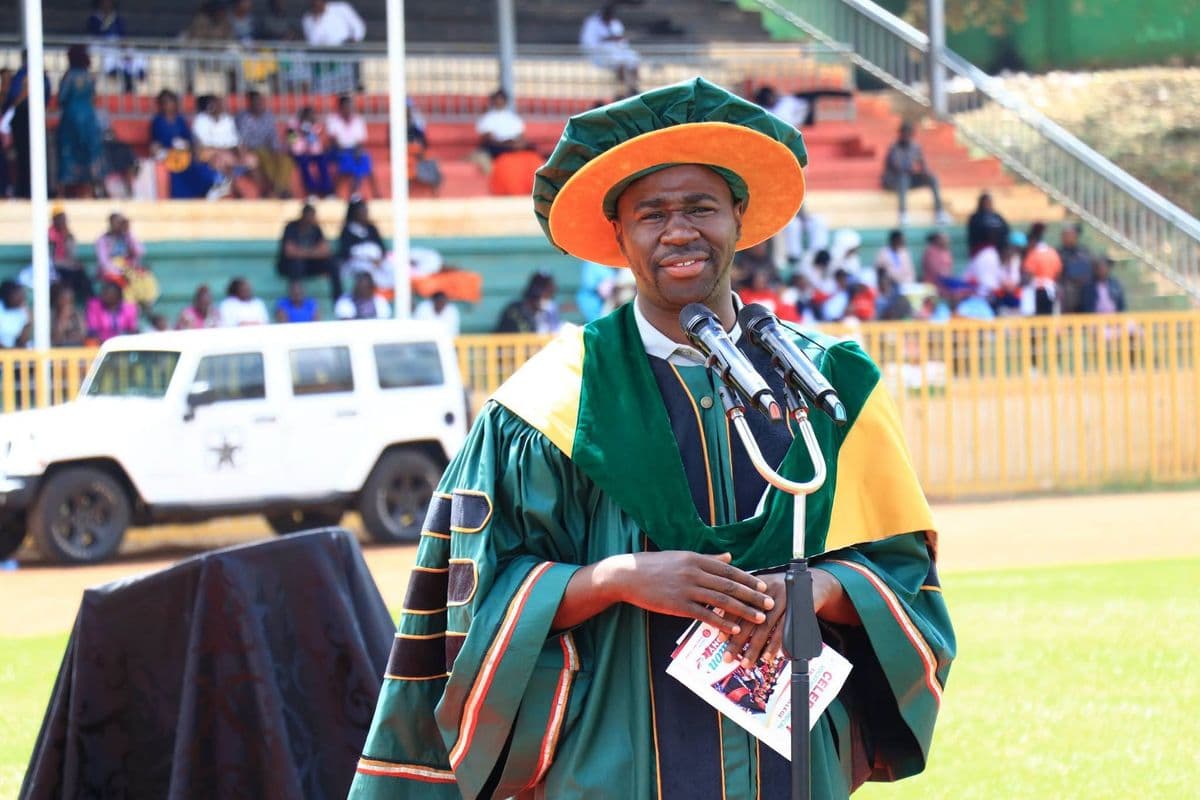 Hon. Mukunji in academic gown speaking at a graduation ceremony